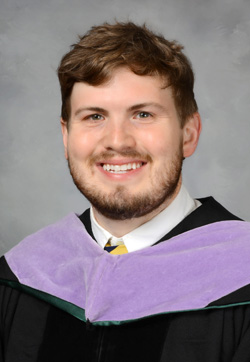 A young man wearing a graduation gown with a purple hood, smiling at the camera.