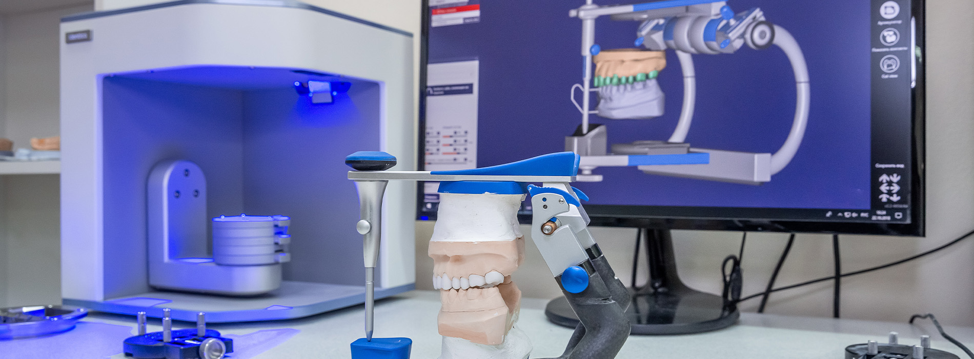 The image shows a laboratory setting with various pieces of equipment, including a microscope on a table, a computer monitor displaying an image of a human mouth, and a machine with blue lights that appears to be used for medical or scientific research.