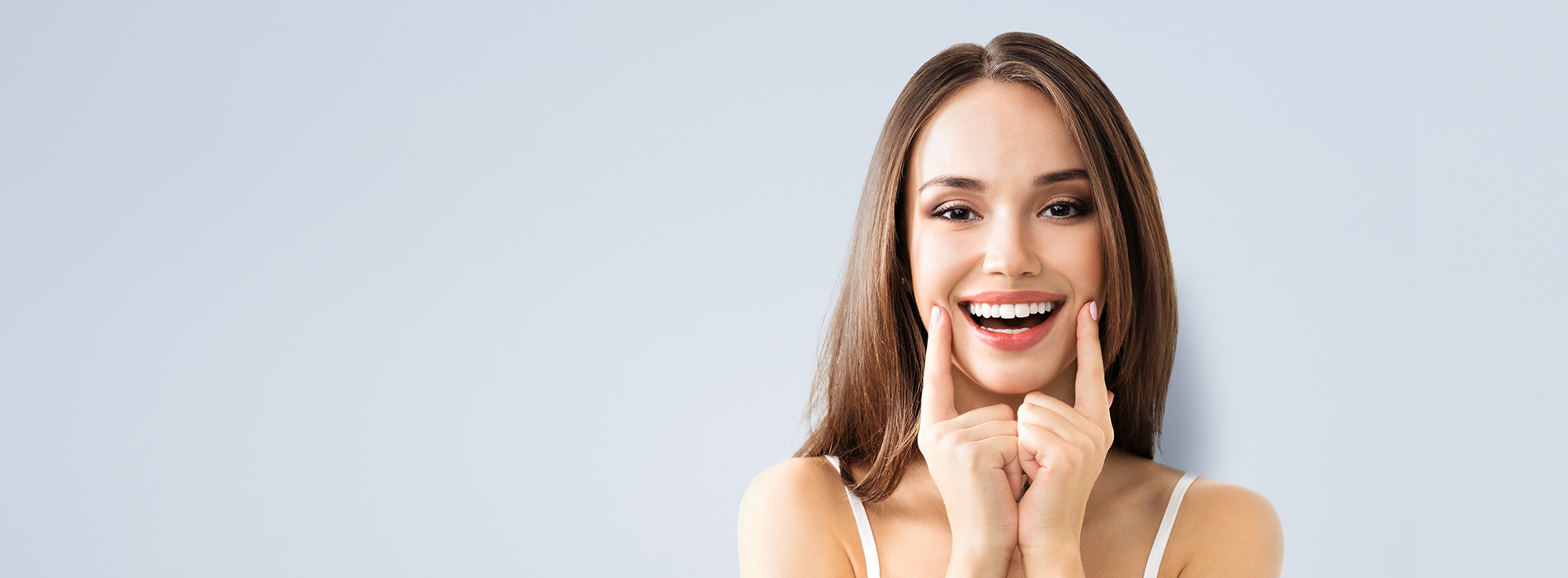 The image shows a woman with her hand on her chin, smiling broadly at the camera, set against a light blue background.