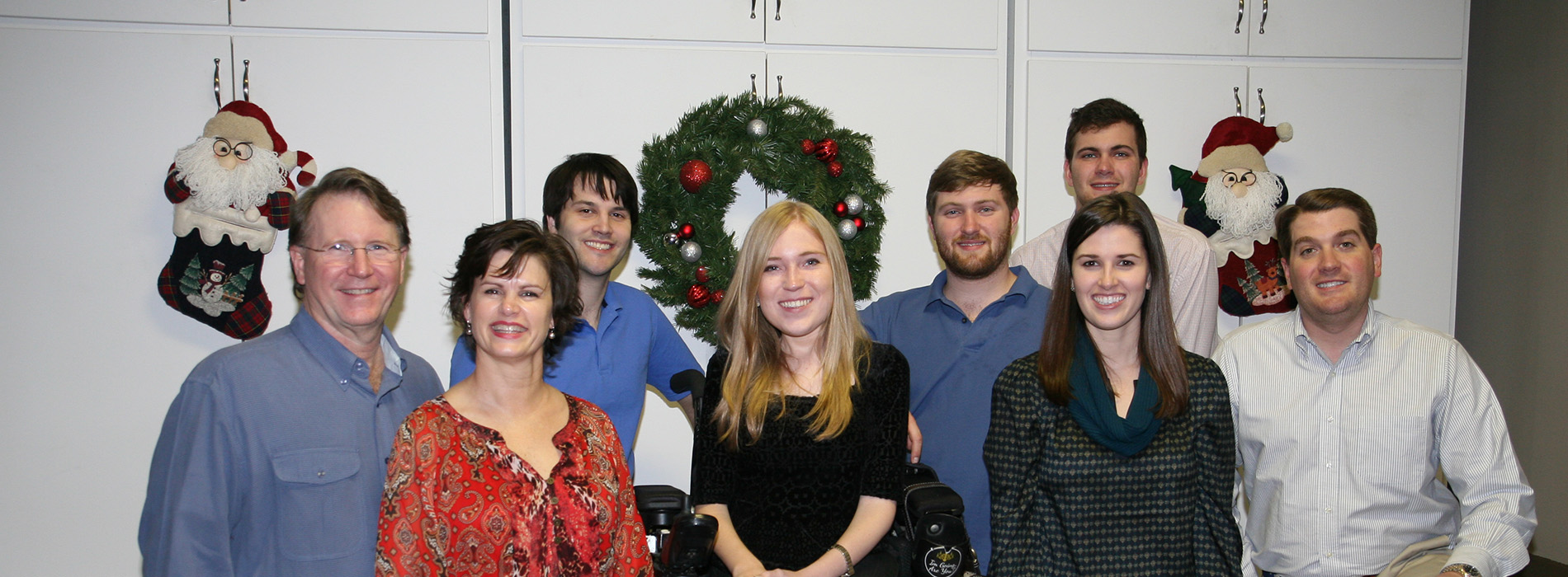 A group of people posing together, likely for a professional or formal occasion, with a festive background featuring holiday decorations.