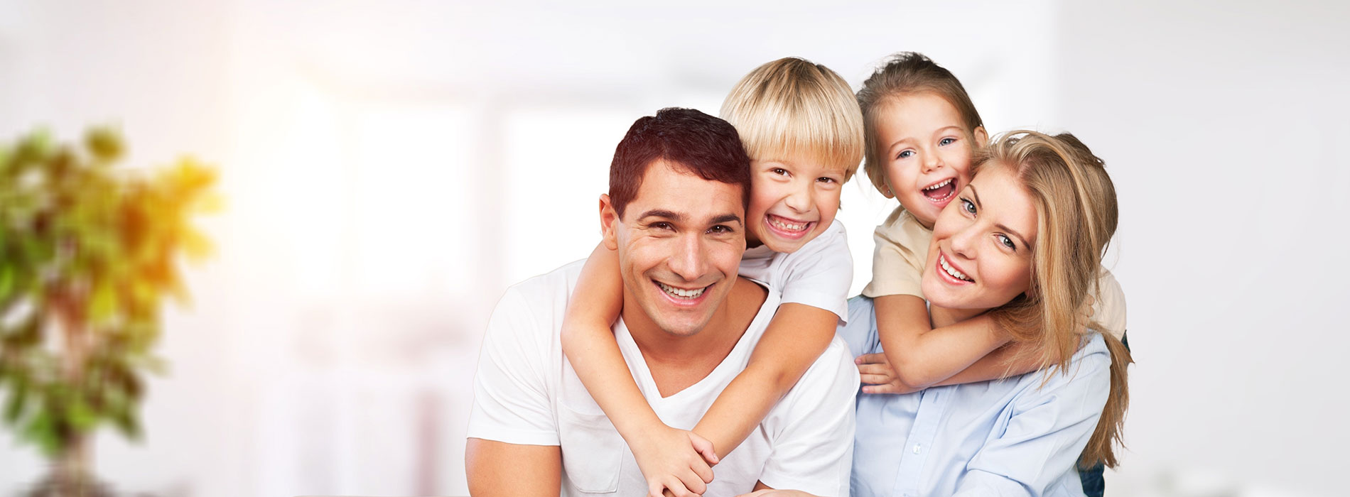 A family of five posing together with smiles, featuring a man, woman, and three children.