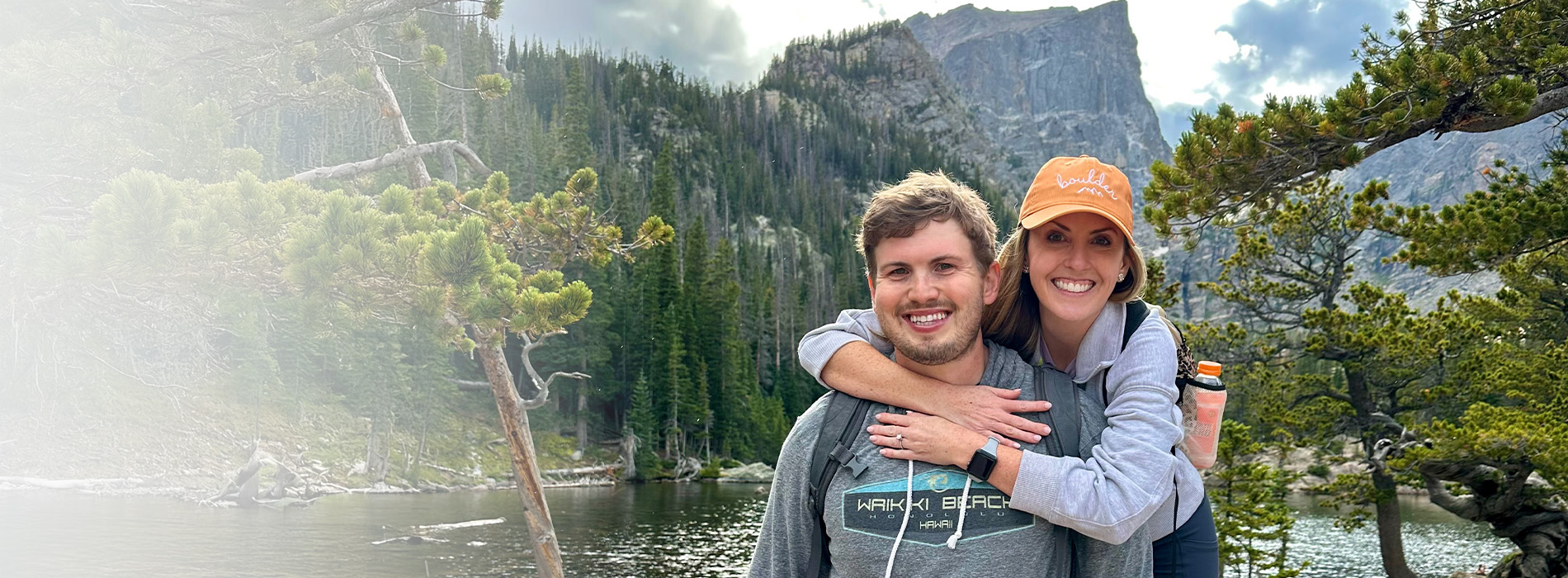 A man and woman posing together outdoors with mountains in the background, possibly at a national park.