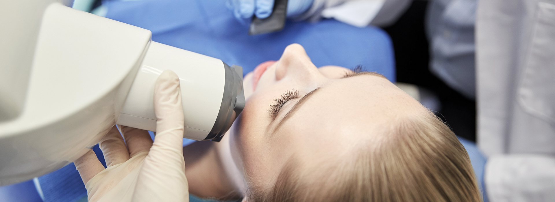 The image depicts a person receiving a medical treatment with a device placed on their head, likely for examination or diagnosis purposes.