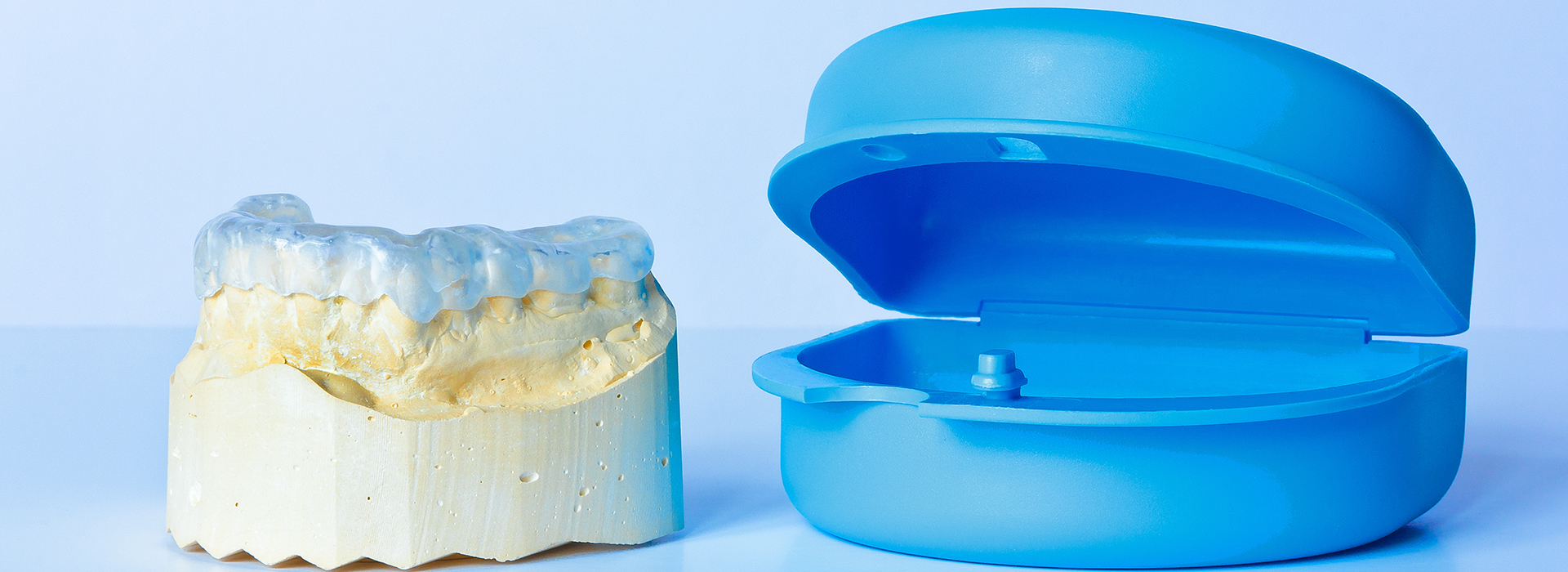 The image shows a blue toothbrush head next to a yellow dental implant component on a white background.