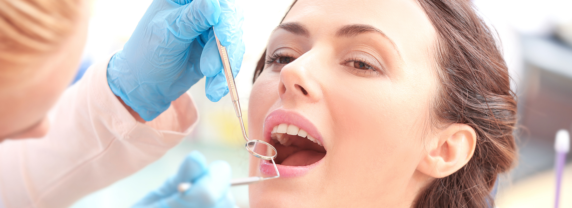 A woman receiving dental care with dental instruments visible.