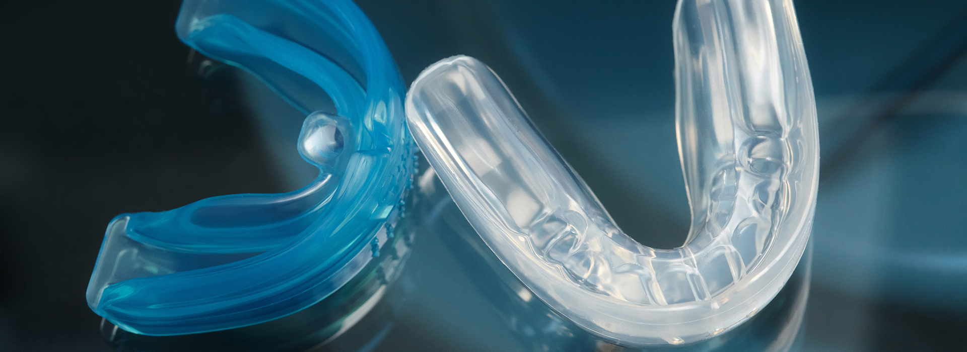 The image shows a close-up of a blue plastic toothbrush with clear bristles against a dark background, emphasizing its color and design.