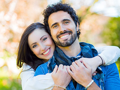 The image shows a man and woman embracing each other with smiles on their faces, likely expressing affection or joy.