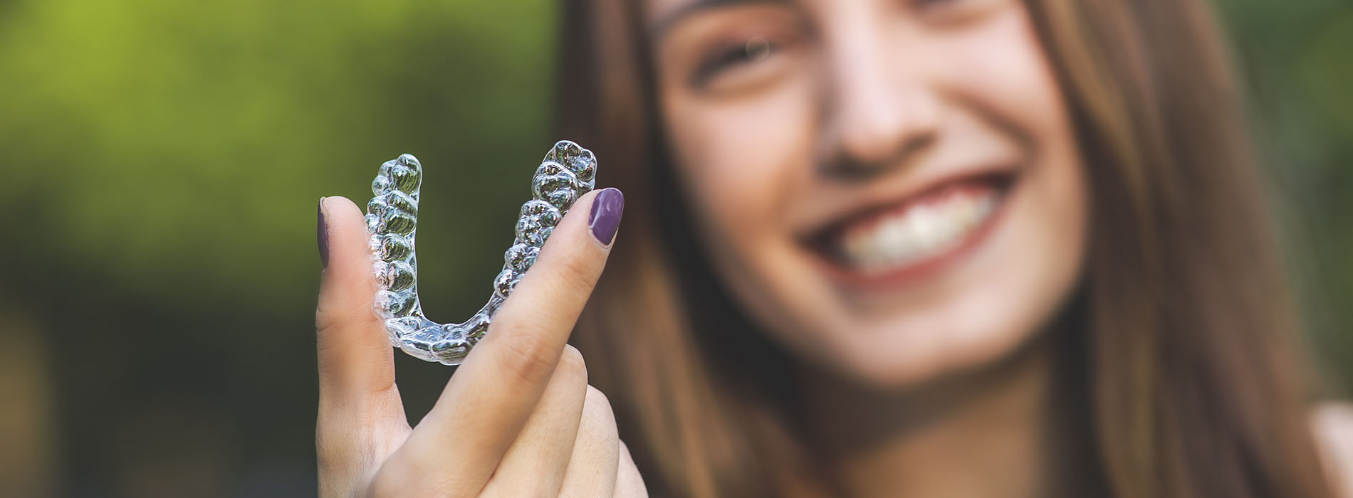 The image shows a smiling person holding a clear plastic object with love written on it.